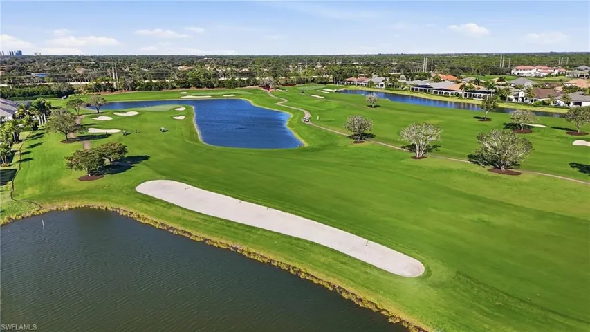 Aerial view of residential area featuring a golf course and a nearby body of water