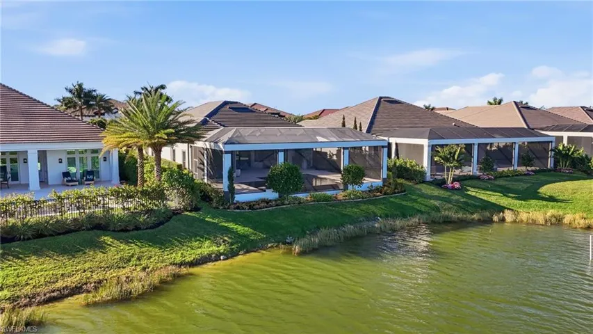Back of property featuring a water view, a lanai, a sunroom, a yard, and a patio