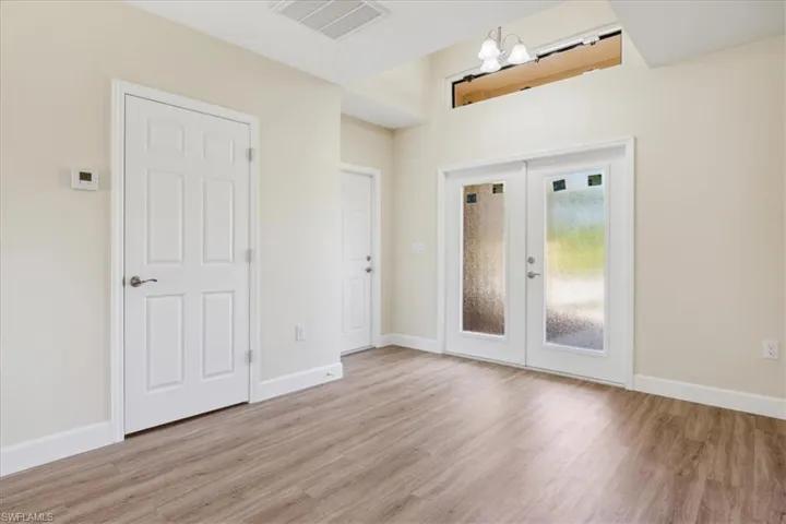 Foyer with light hardwood / wood-style flooring, french doors, and an inviting chandelier
