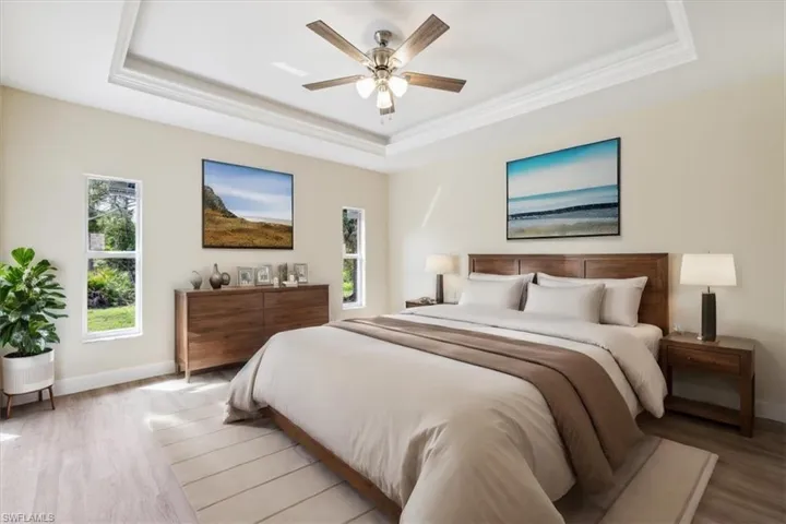 Bedroom featuring ceiling fan, hardwood / wood-style flooring, and a tray ceiling