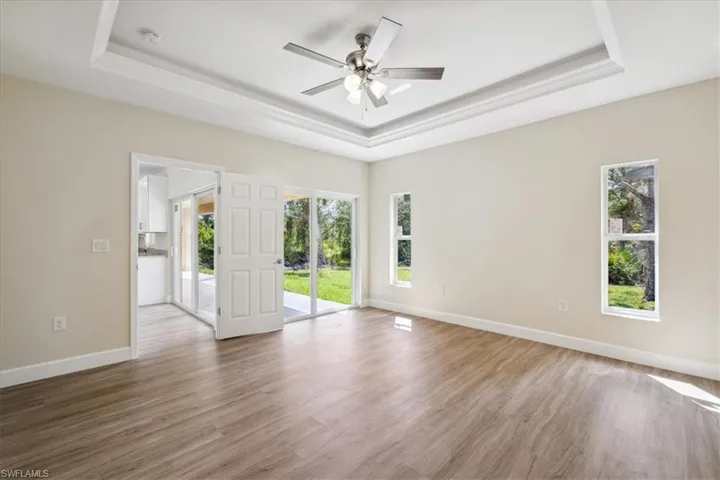 Empty room featuring ceiling fan, hardwood / wood-style floors, and a tray ceiling