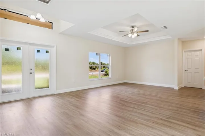 Empty room featuring light wood-type flooring, a tray ceiling, and ceiling fan
