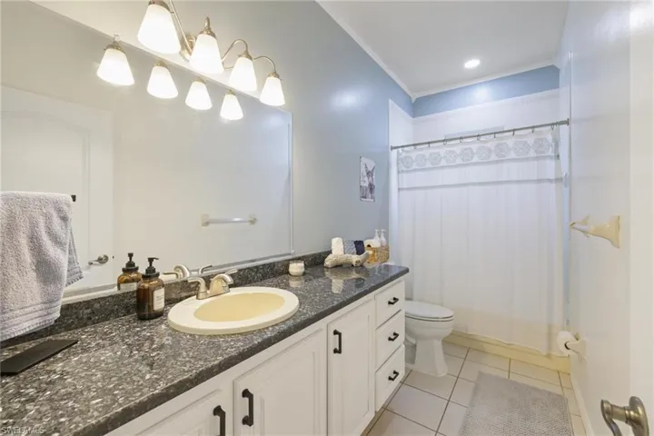 Full bathroom featuring vanity, a shower with shower curtain, light tile patterned floors, crown molding, and recessed lighting