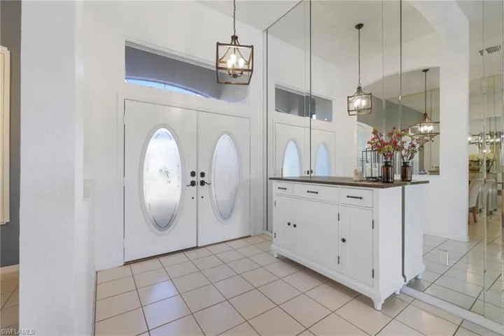 Foyer entrance with light tile patterned flooring and a chandelier