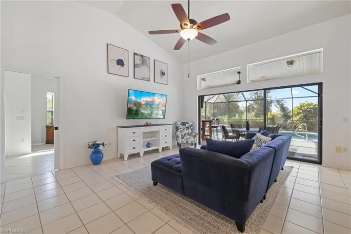 Living area featuring a sunroom, a ceiling fan, light tile patterned flooring, and high vaulted ceiling