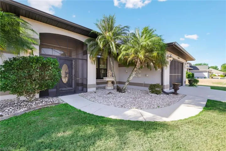 Doorway to property with stucco siding, a lawn, and a sunroom