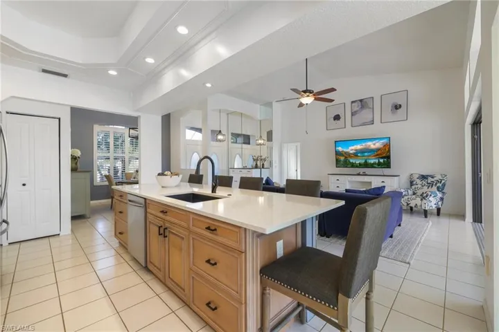 Kitchen featuring a breakfast bar, light stone countertops, open floor plan, a kitchen island with sink, and brown cabinets