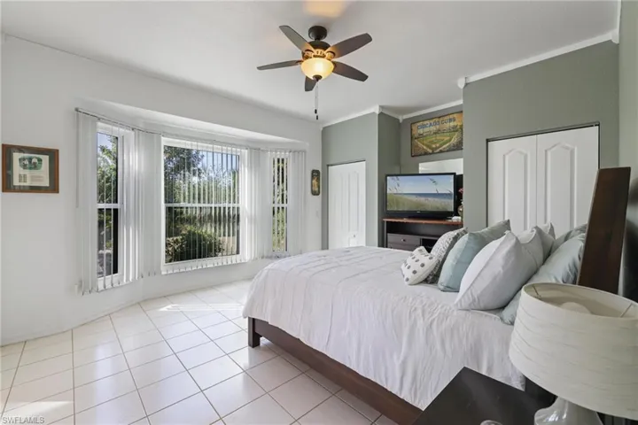 Bedroom featuring multiple closets, tile patterned floors, a ceiling fan, and crown molding