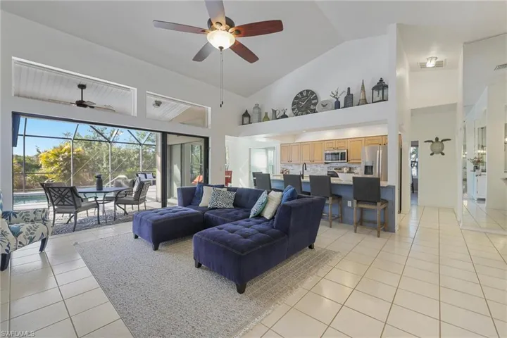 Living room featuring a sunroom, a ceiling fan, light tile patterned floors, and high vaulted ceiling