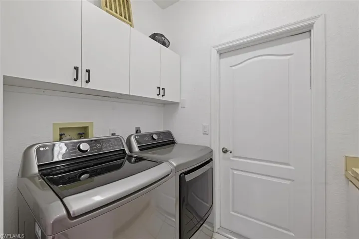 Laundry room with cabinet space, a textured wall, and washing machine and dryer