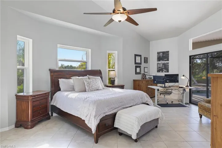 Bedroom featuring a desk, access to outside, lofted ceiling, multiple windows, and ceiling fan