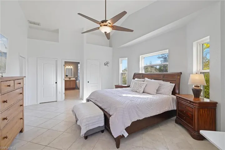 Bedroom featuring a towering ceiling, ceiling fan, ensuite bathroom, and a closet