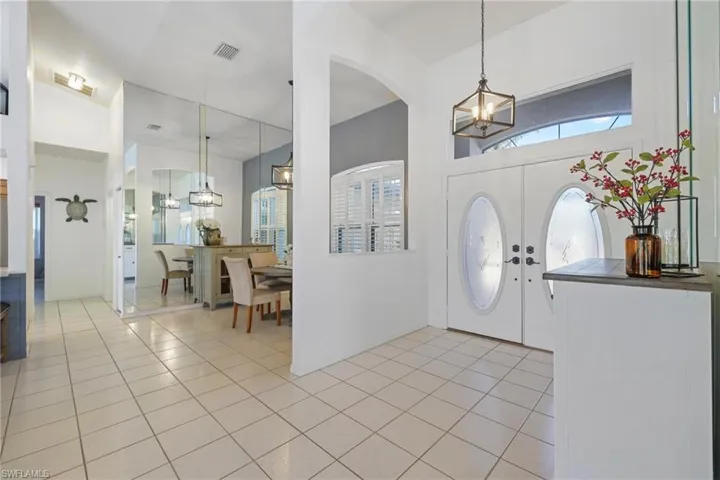 Foyer featuring a chandelier, healthy amount of natural light, light tile patterned floors, a towering ceiling, and french doors