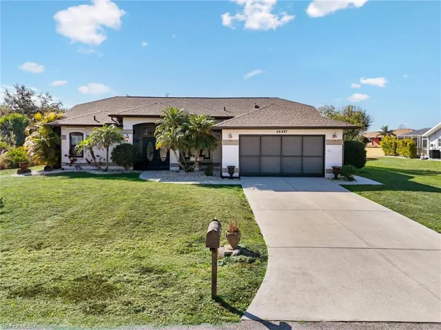 Single story home featuring a front lawn, driveway, stucco siding, an attached garage, and a shingled roof
