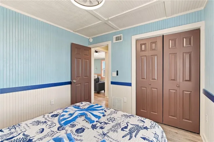 Room featuring vertical beadboard paneling with chair rail molding, coffered ceiling detail, and double-door closet with six-panel doors - Virtually Edited Image