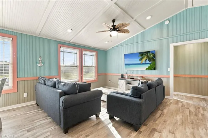 Vaulted ceilings with beadboard paneling, wood-finish flooring, dual-tone wall paneling, and a central ceiling fan - Virtually Edited Image
