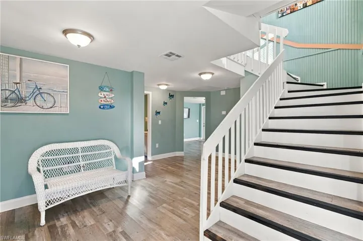 Staircase featuring white balusters, wood-finish treads with dark trim, and vertical wood-plank wall paneling - Virtually Edited Image