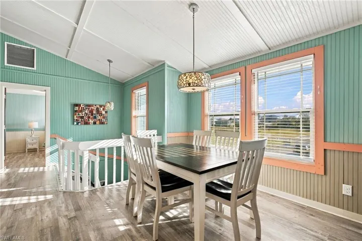 Vaulted beadboard ceilings, wood-finish flooring, vertical paneling, and dual pendant light fixtures - Virtually Edited Image