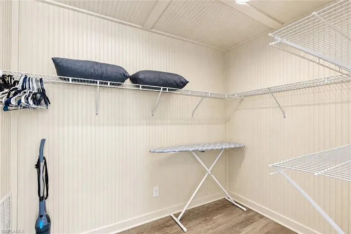 Storage space featuring vertical beadboard paneling, wood-finish flooring, and multi-tier wire shelving - Virtually Edited Image