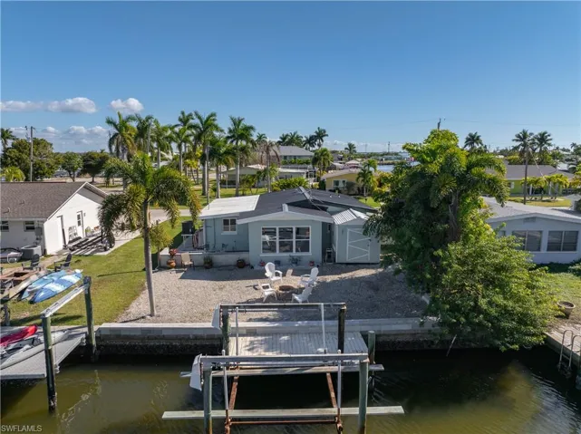 Dock with a water view, boat lift, a residential view, and a lawn