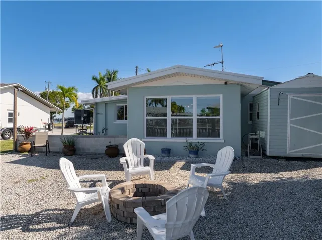 Rear view of house featuring a storage unit and an outdoor fire pit