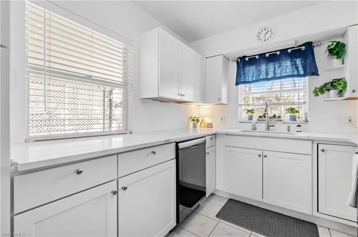 Kitchen with white cabinetry, black dishwasher, light stone counters, open shelves, and light marble finish floors
