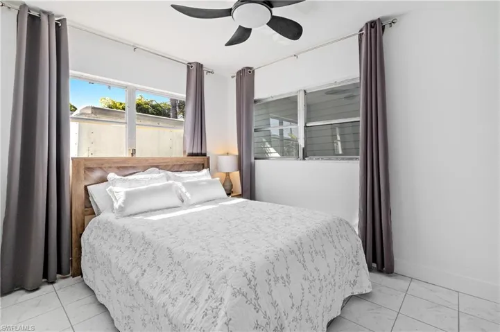 Bedroom featuring a ceiling fan and light marble finish flooring