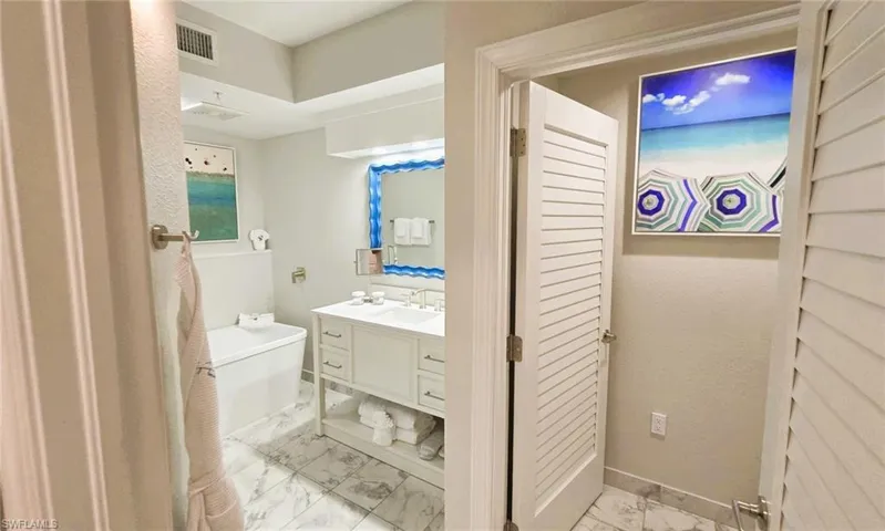 Full bathroom featuring vanity, a freestanding tub, and light marble finish floors