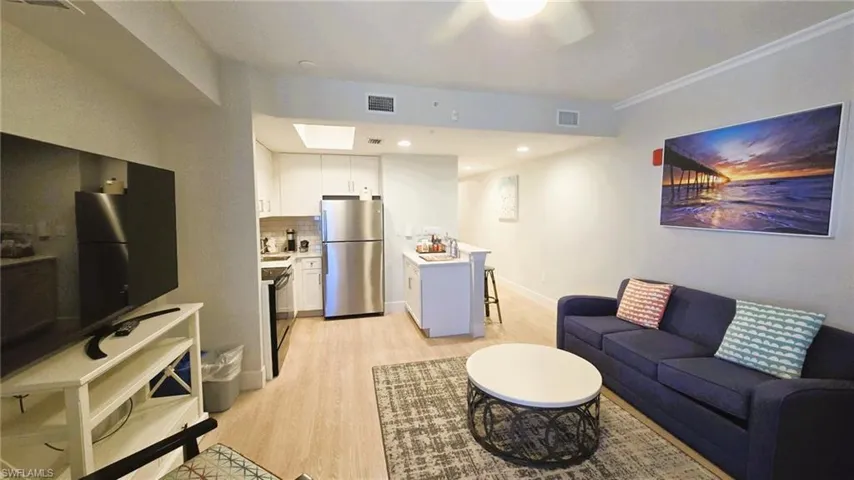 Living room featuring light wood-style flooring, recessed lighting, and a skylight