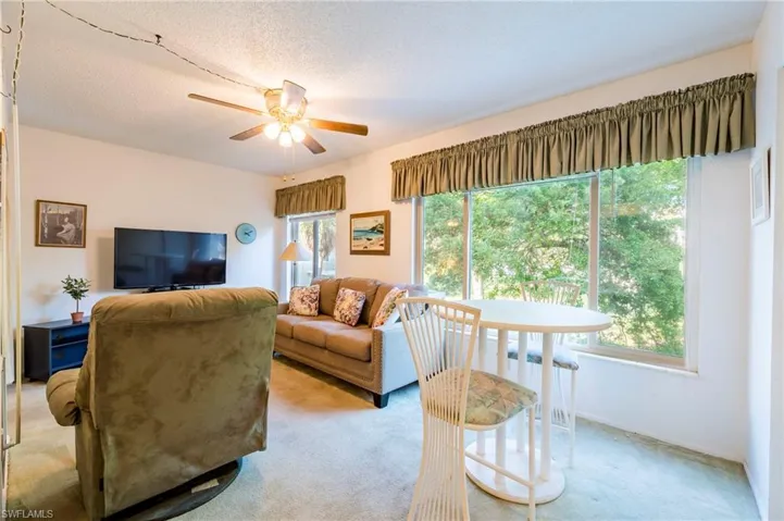 Living room with light carpet, ceiling fan, and a textured ceiling