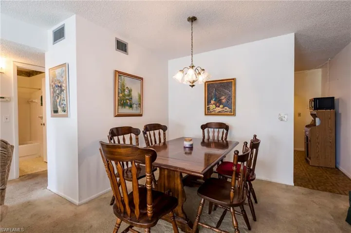 Carpeted dining space with a textured ceiling and an inviting chandelier