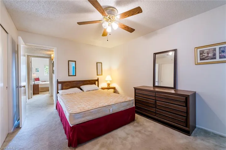 Bedroom with light carpet, ceiling fan, and a textured ceiling