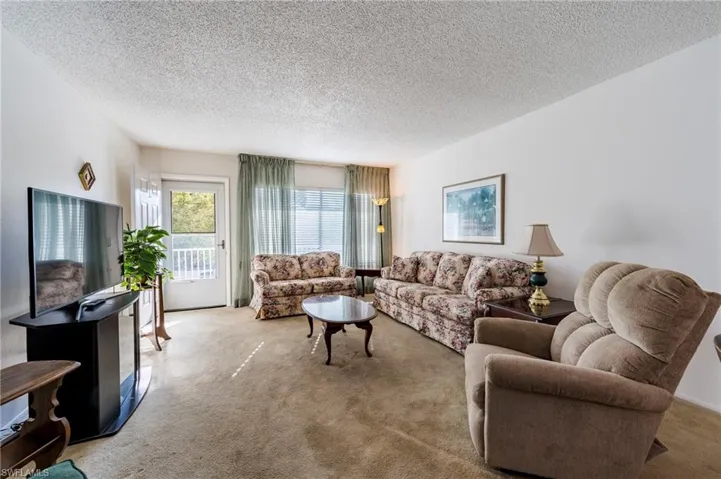 Living room featuring light colored carpet and a textured ceiling