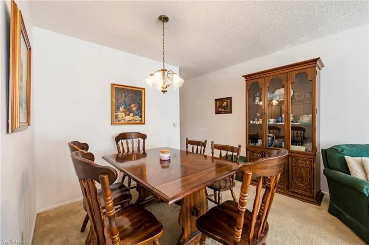 Dining room with an inviting chandelier, a textured ceiling, and light colored carpet