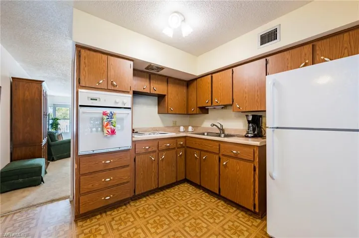Kitchen featuring a textured ceiling, white appliances, and sink