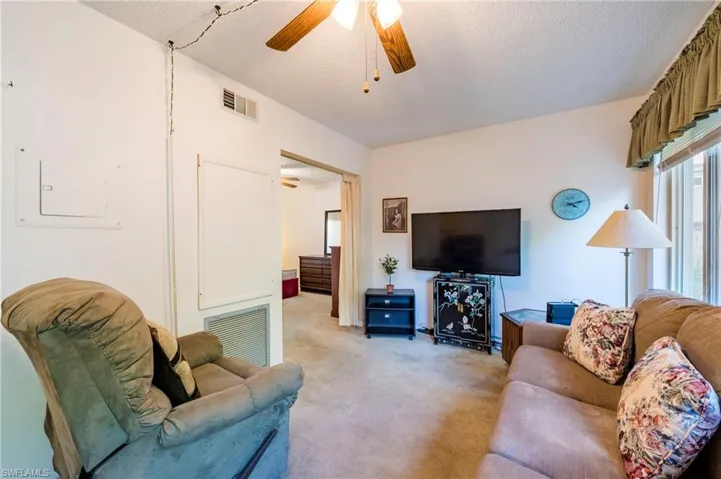 Carpeted living room with ceiling fan and a textured ceiling