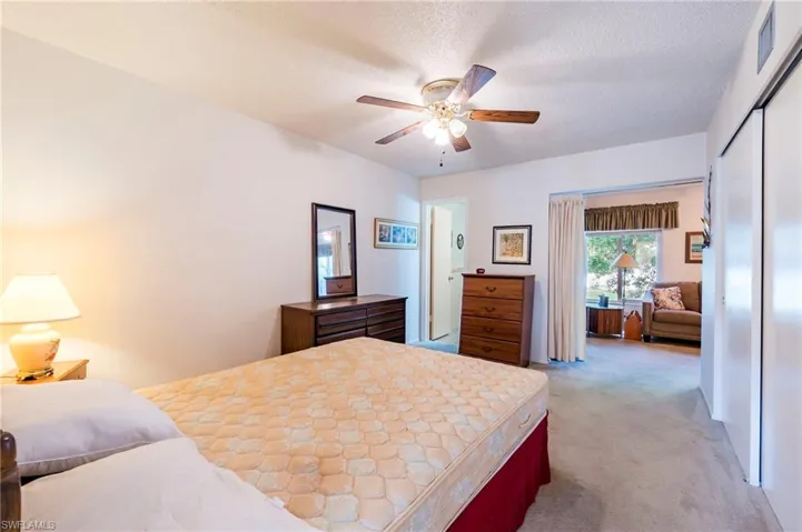 Bedroom with a textured ceiling, carpet, ceiling fan, and a closet