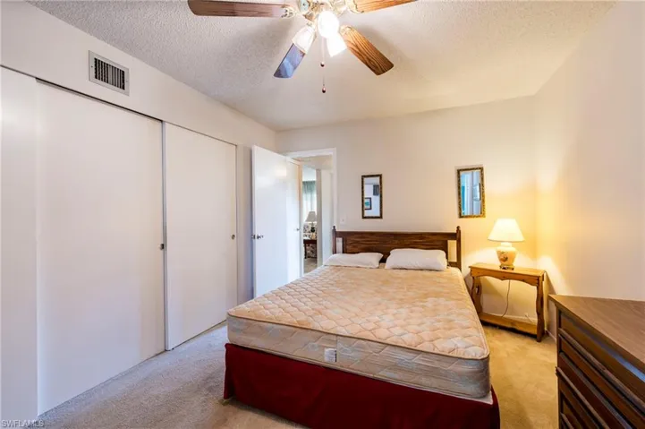 Bedroom with a closet, ceiling fan, light colored carpet, and a textured ceiling