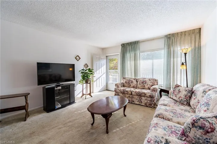 Carpeted living room with a textured ceiling