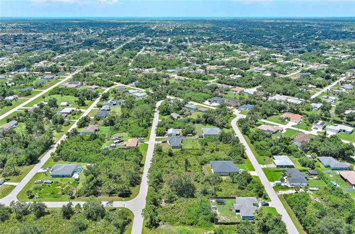 Aerial overview of property's location featuring a tree filled landscape and nearby suburban area
