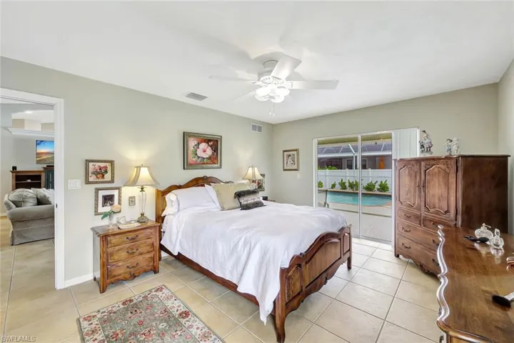 Bedroom with ceiling fan, light tile patterned floors, and access to exterior