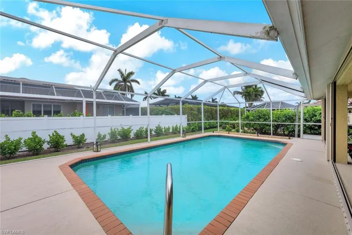 View of swimming pool featuring glass enclosure and a patio area