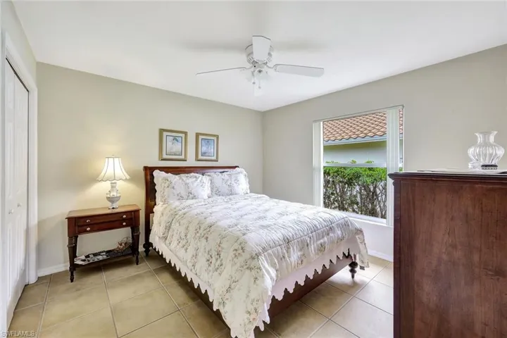 Bedroom with ceiling fan, light tile patterned floors, and a closet