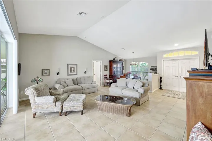 Tiled living room featuring lofted ceiling
