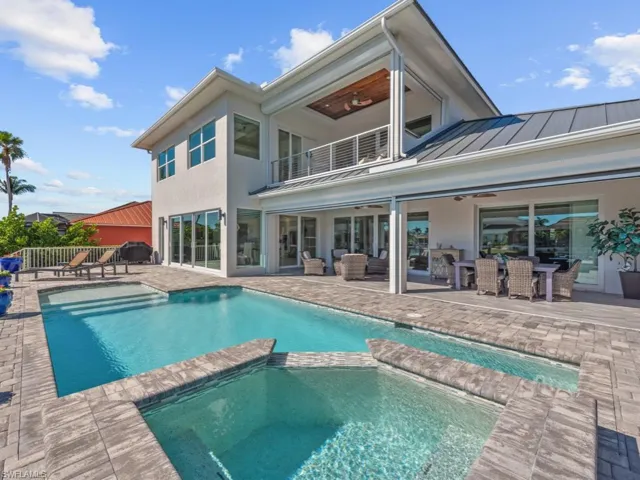 Back of house with a balcony, ceiling fan, a patio area, and a pool with hot tub