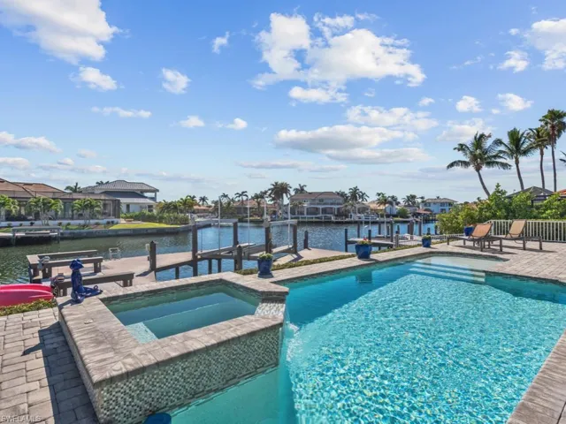 View of pool with a patio area, a water view, an in ground hot tub, and a dock