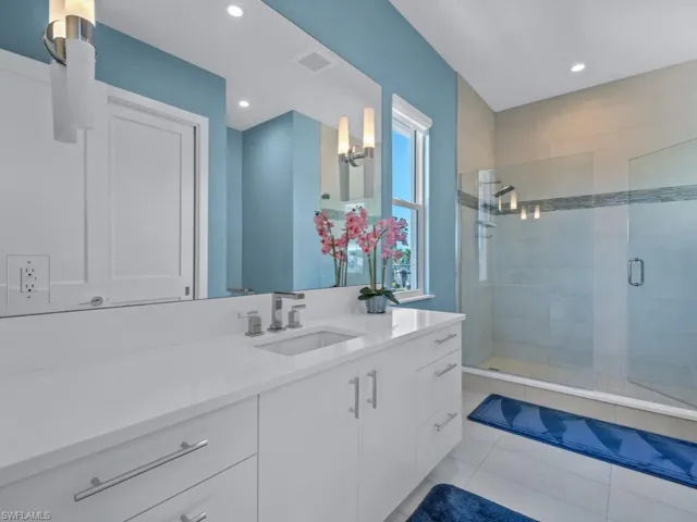Bathroom featuring tile patterned floors, vanity, and a shower with door