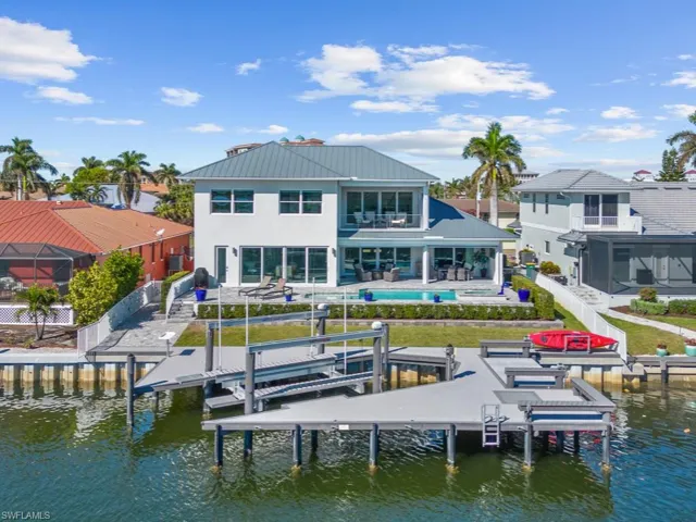 Back of property featuring a balcony, a water view, and a pool