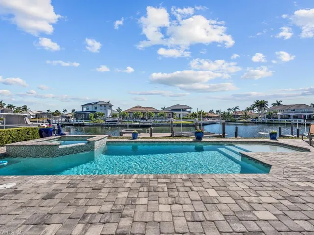 View of swimming pool featuring a patio area, an in ground hot tub, a water view, and a boat dock