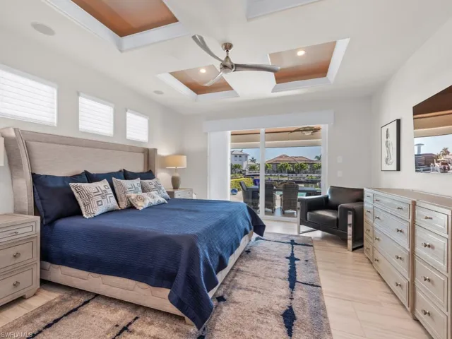 Bedroom featuring ceiling fan, access to exterior, and a tray ceiling